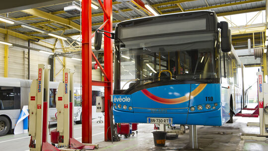 Photo de l'intérieur de l'atelier avec un bus posé sur un pont élévateur